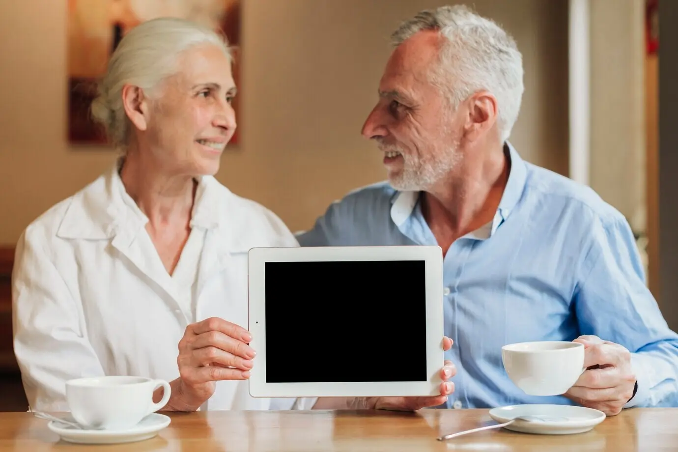 Plano medio de una pareja sosteniendo una maqueta de una tableta